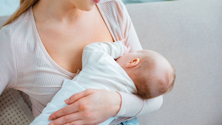 cropped shot of young woman breastfeeding infant baby at home