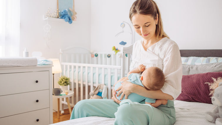 mother breastfeeding her baby in at-home nursery