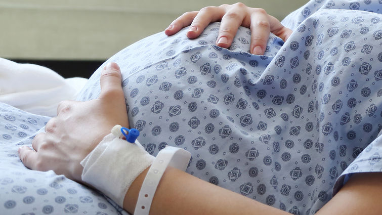 pregnant women in hospital gown holding baby