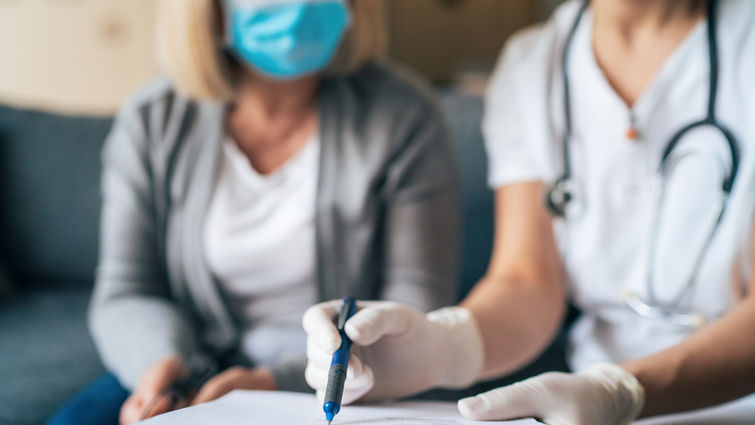 physician sits with patient using clipboard