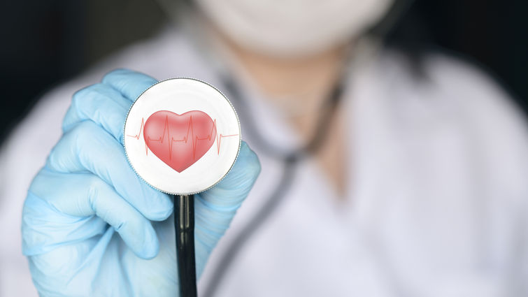 Masked physician holding up a stethoscope with a heart icon and heartbeat on it