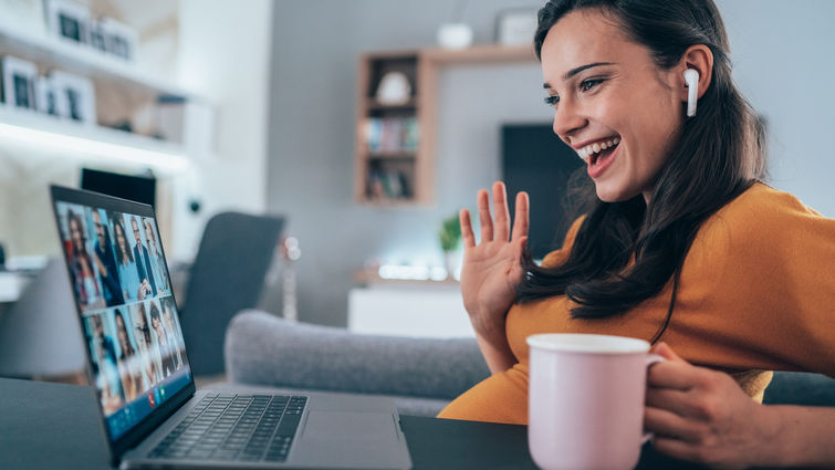 pregnant woman having video online meeting using her laptop and Wireless earbuds at home