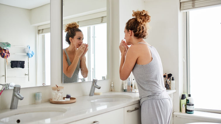 Woman smelling her breath while looking in the mirror 