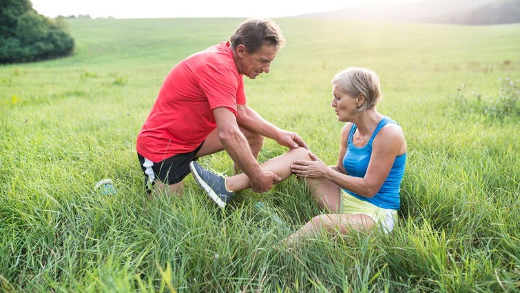 Male helping female with knee pain while hiking