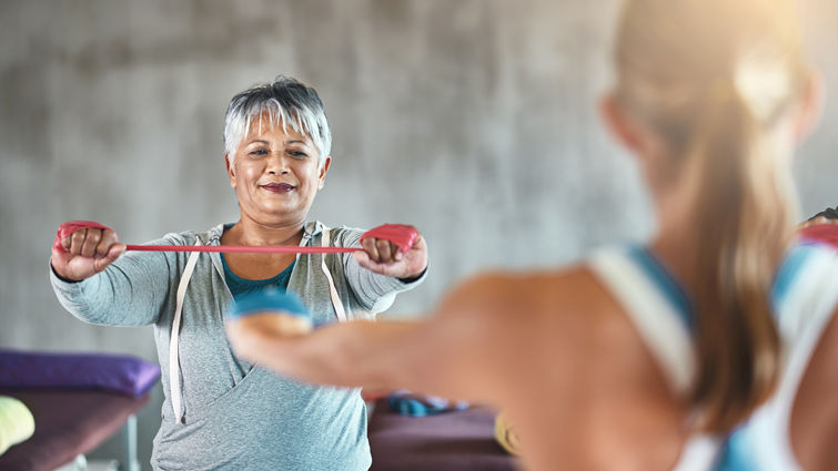 Woman exercising arms during a class while facing another woman