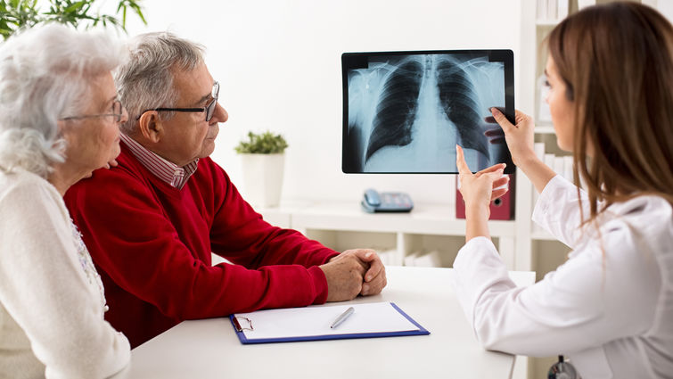 Physician showing older couple x-rays of lungs