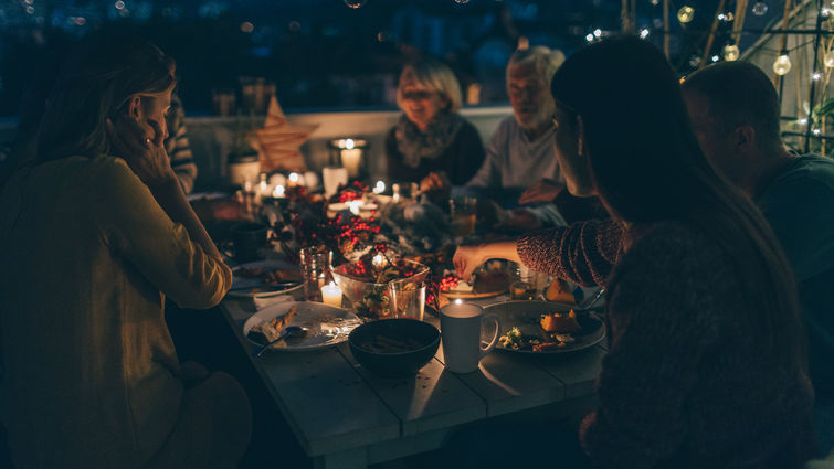 multigenerational family enjoys outdoor thanksgiving meal together after dark