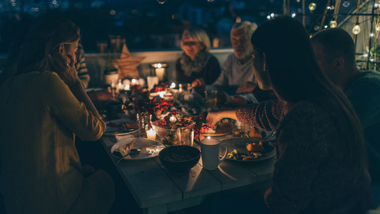 multigenerational family enjoys outdoor thanksgiving meal together after dark