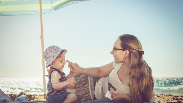 Young mother applying sunblock cream on her baby