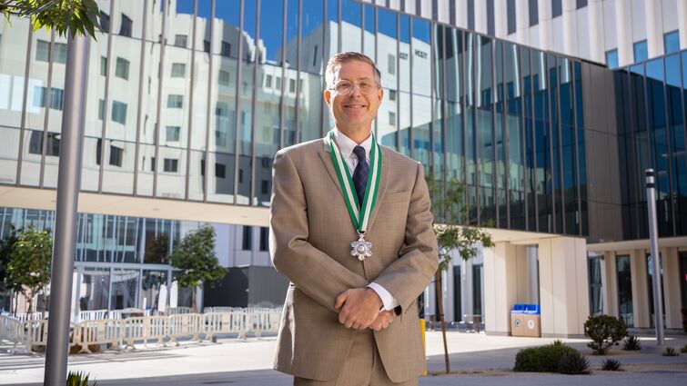 Dr. Forrest Jellison standing outside in fornt of the LLU Medical Center building in a tan suit wearing a medal