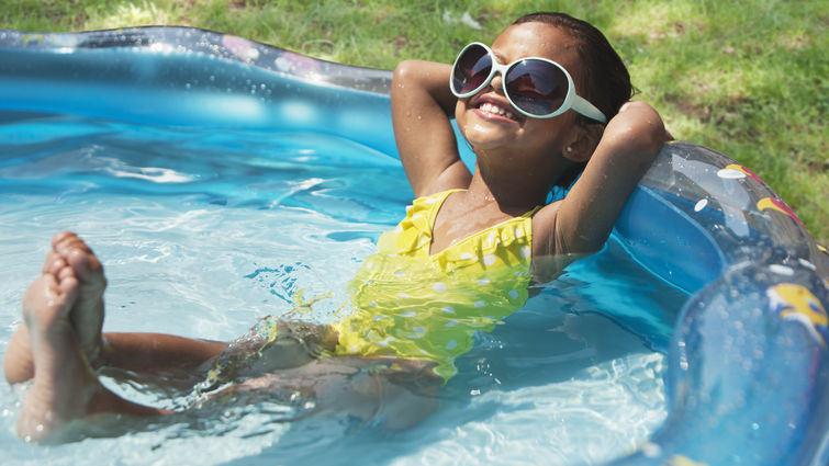 Hispanic girl relaxing in kiddie pool 