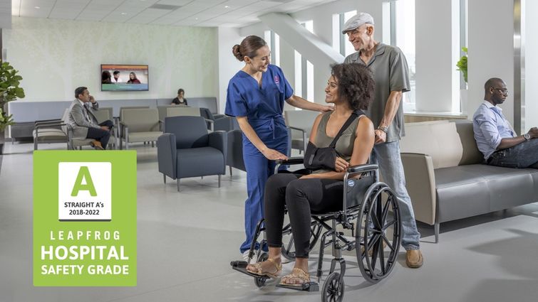 Woman in wheelchair, speaking to clinician in scrubs at a hospital