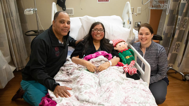 doctor poses with patient mom and medical staffer