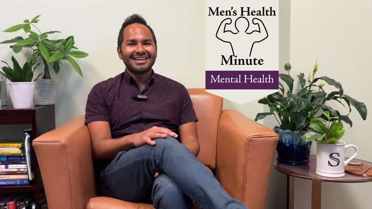 A man in a purple button up shirt sits in a cushioned orange chair in a therapist office. There are plants on side tables