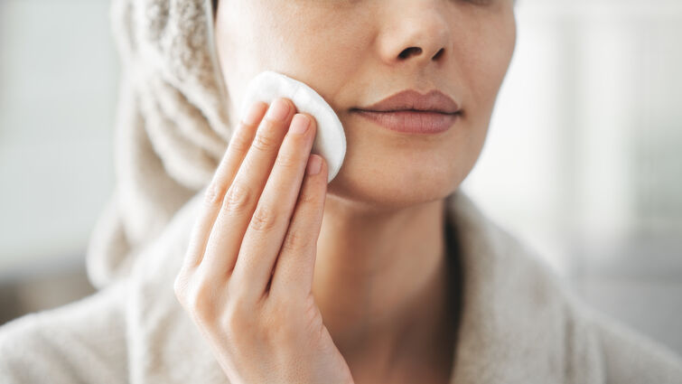 Woman swiping cotton pad across skin