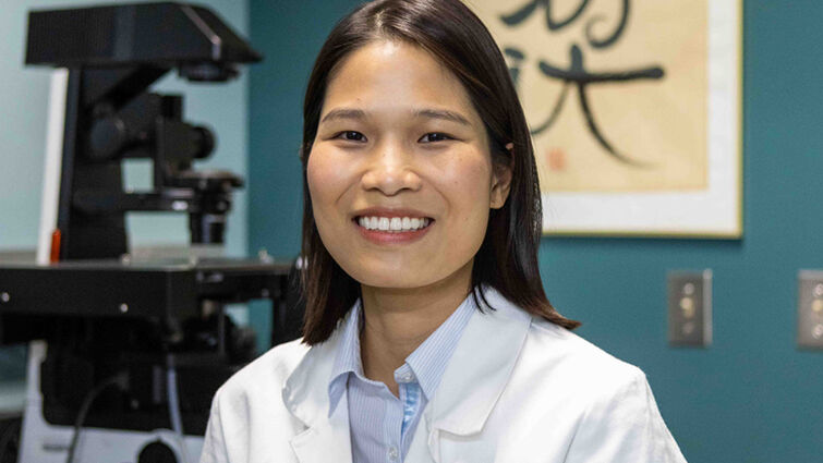 A doctor in a white lab coat smiles at the camera