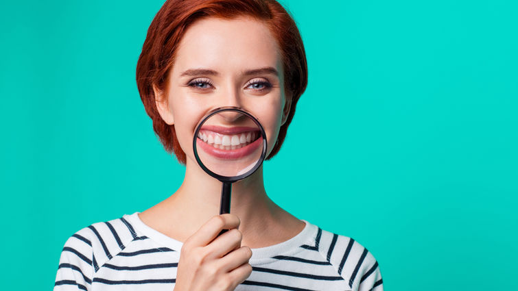 Woman holding a magnifying glass in front of teeth