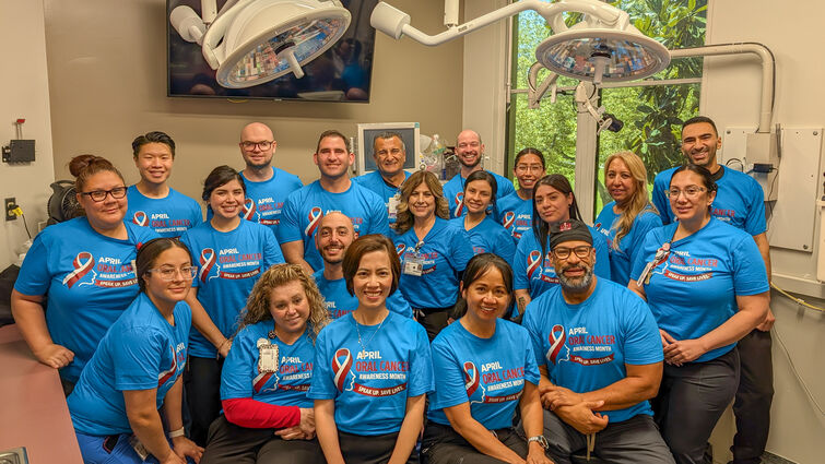 A group of people in blue shirts stand together in a dental office