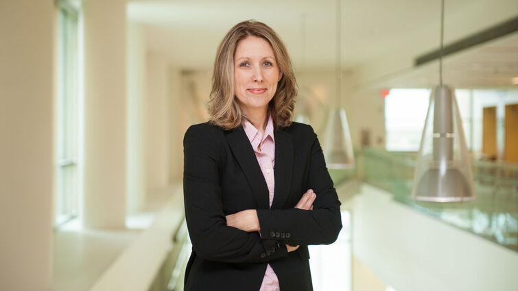 Rhonda Spencer-Hwang, DrPH, MPH standing inside the hospital with her arms crossed