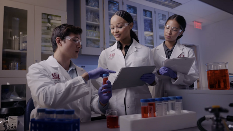 a group of people are in a medical setting looking over a vile of medication 