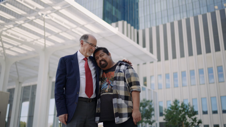 a man in a suit is hugging another man while smiling