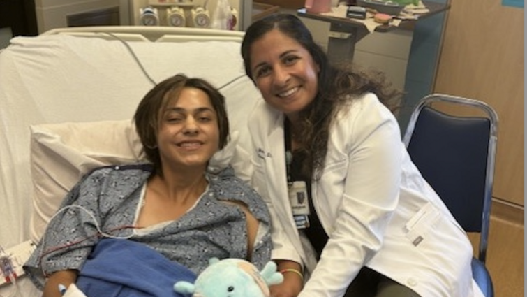 Patient Jesse Campos smiles while on hospital bed next to Dr. Tanya Minasian