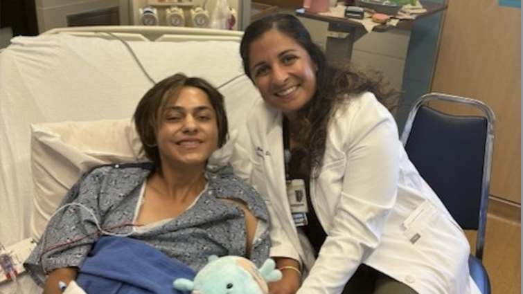 Patient Jesse Campos smiles while on hospital bed next to Dr. Tanya Minasian