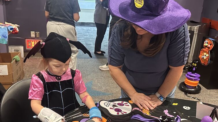 volunteer helps child with festive craft