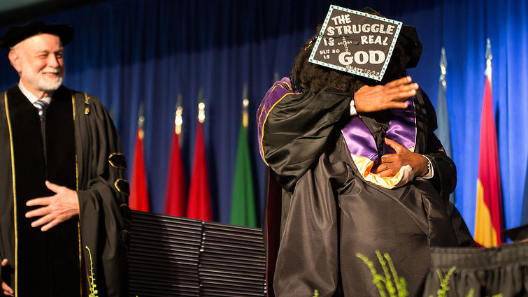Wearing her heart on her hat, a student of Loma Linda University School of Allied Health Professions gets a hug from Dean Jackson while President Hart looks on. lluh