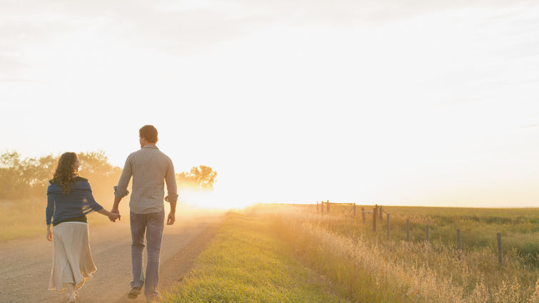 Couple walking toward a sunset on a dirt road