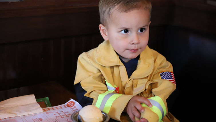 This young spaghetti fan enjoyed being served by firefighters during Tip-A-Firefighter during the dinner shift on Wednesday, May 30. boy in a firefighter uniform