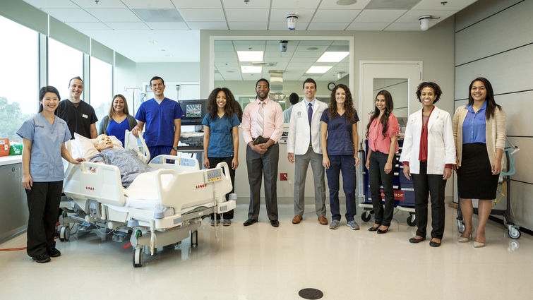 Loma Linda University staff of nurses, physicians and faculty stand in the middle of a patient's room. 