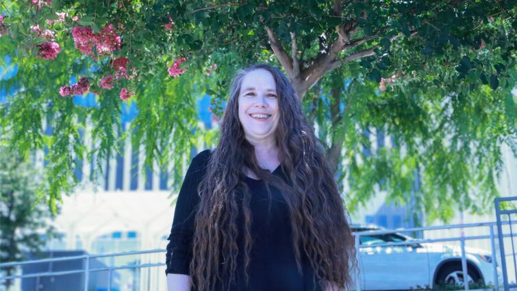 Wendy De La Pena stands outside of hospital underneath green tree