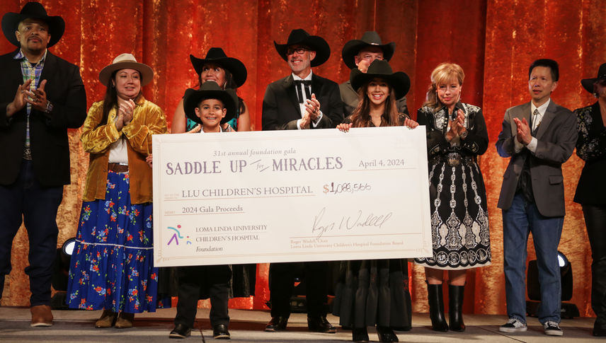 group wearing country-themed attire, including two young children, present a large check