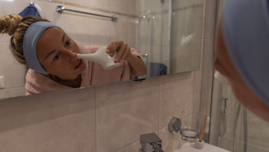 Woman using a natural nasal saline irrigation to clean her nose. Neti pot - stock photo