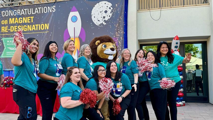 Group of people outside in matching teal t-shirts smiling at the camera