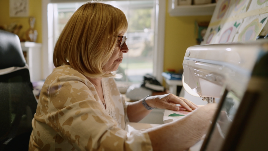 A woman is sitting in a chair using a sewing machine