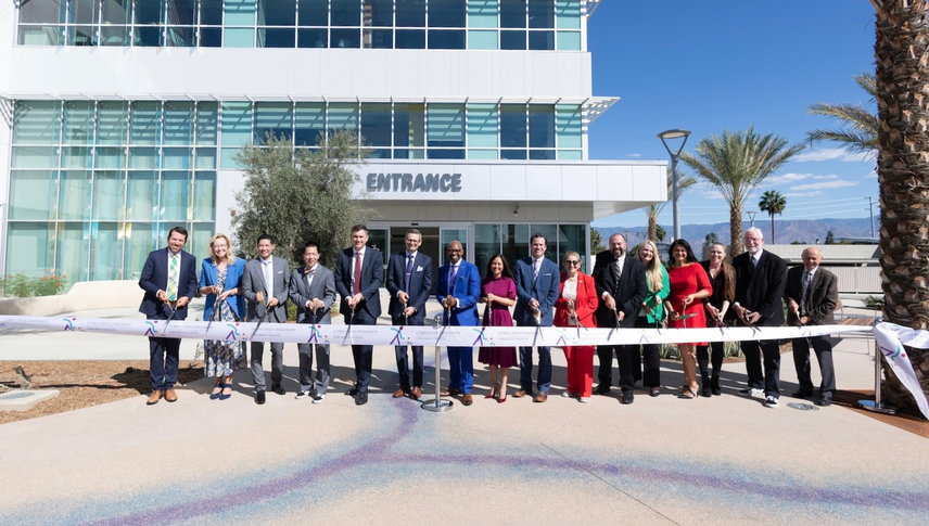 LLUH leaders pose for photo behind long ribbon with large scissors