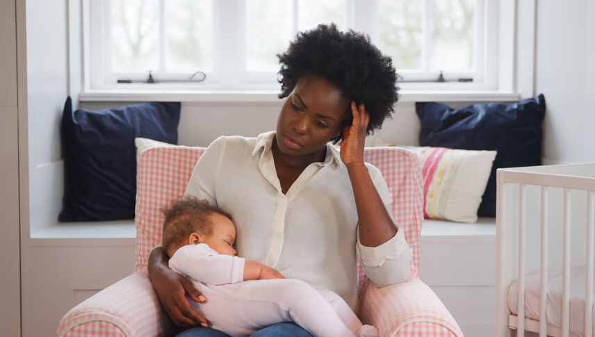 New Mother Suffering With Post Natal Depression Holding Sleeping Baby Daughter In Nursery At Home