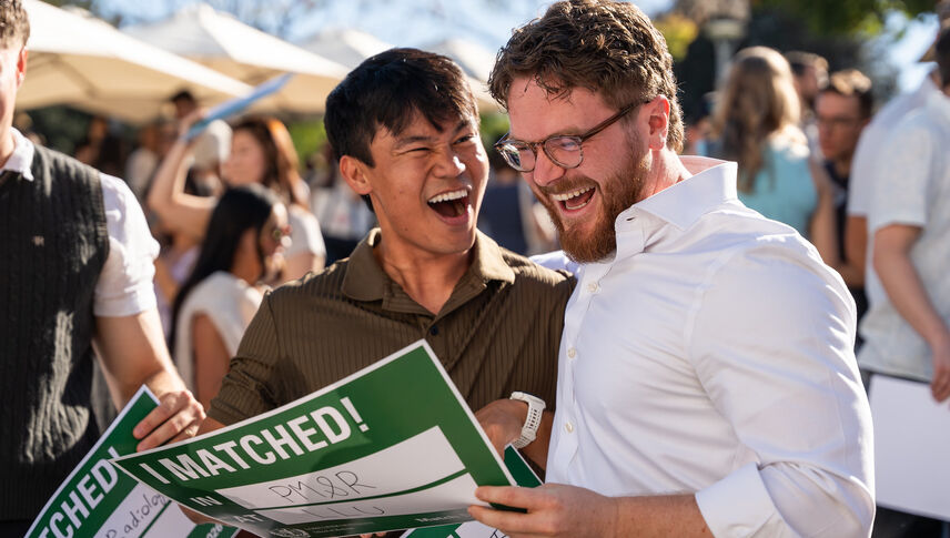 Asian man and Caucasian man outside smiling as they learned their fate at match day 2026