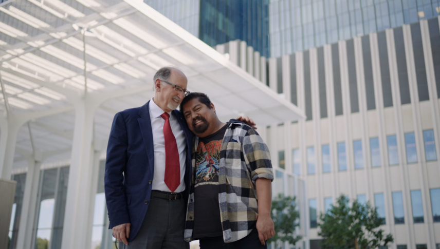 a man in a suit is hugging another man while smiling