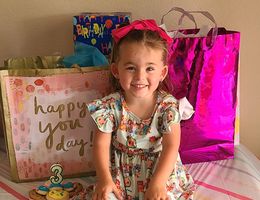 little girl sitting on table with birthday presents and decorations