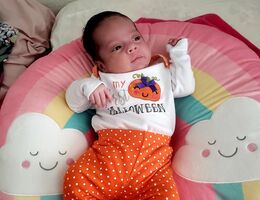 baby laying on rainbow pillow