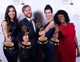 four people hold trophies