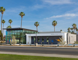 wide shot of concrete and dichroic glass building framed by beautiful blue sky and picturesque palm trees