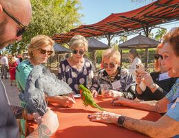 Group of luncheon attendees surround table and admire birds