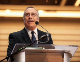 a man is standing in front of a podium with a microphone talking out to an audience 
