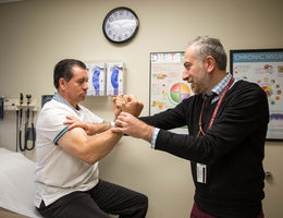 Male physician tests male patient's strength