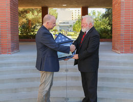 Two male professors shake hand over American flag