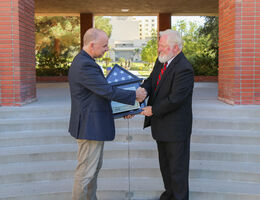 Two male professors shake hand over American flag